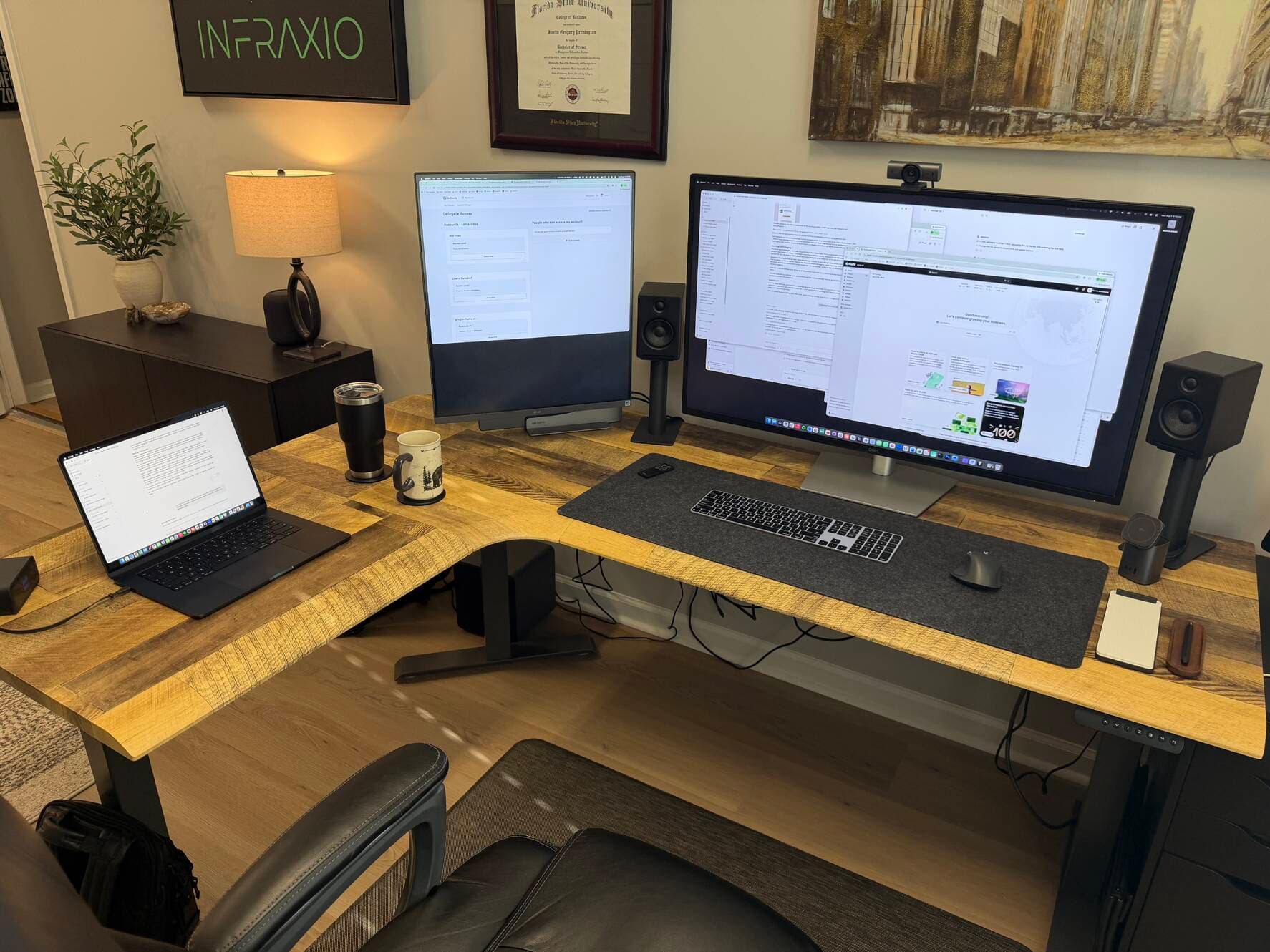 Justin's desk at Infraxio: L-shaped wood desk, laptop, and two large displays