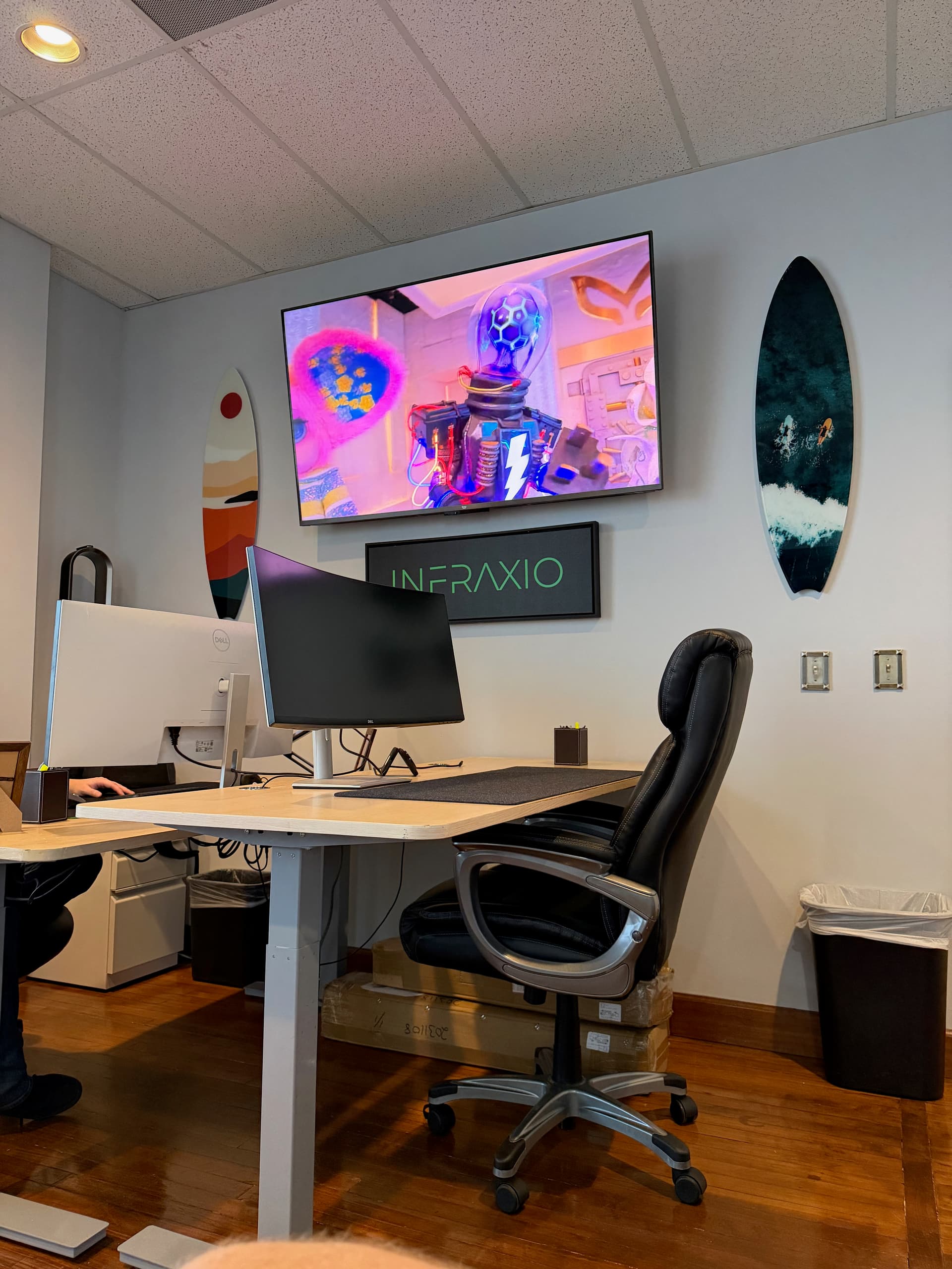 Infraxio workspace with dual monitors, surfboard decor, and the Infraxio sign